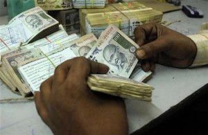 An employee counts currency notes at a cash counter inside a bank in Agartala