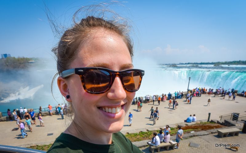 Young smiling woman wearing sunglasses at Niagara Falls.